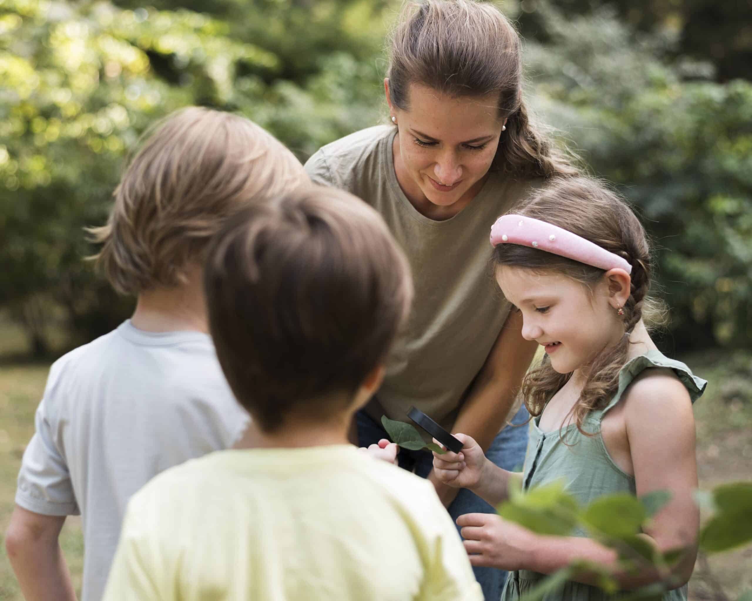 enseignante qui explique à trois enfants les caractéristiques des feuilles